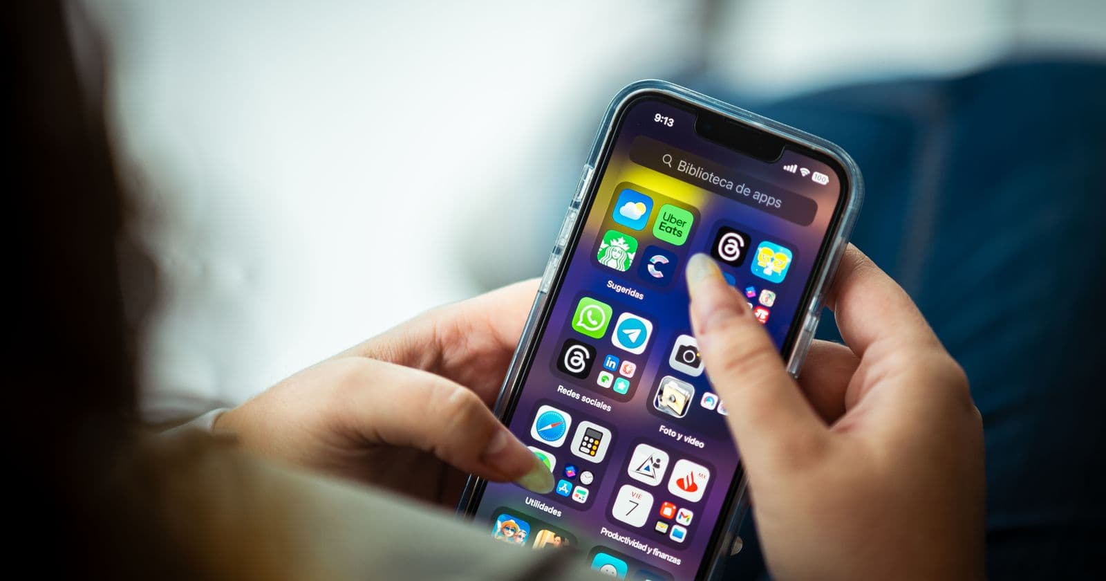 Hands holding a smartphone showing a grid of app icons