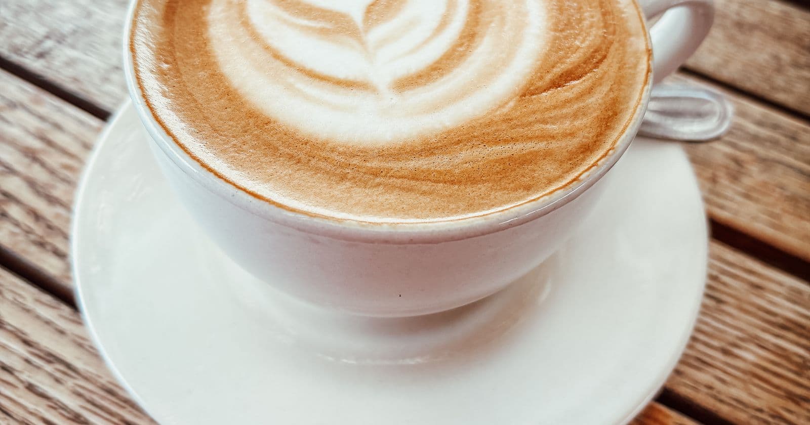 Latte with leaf art in a cup on a wooden table