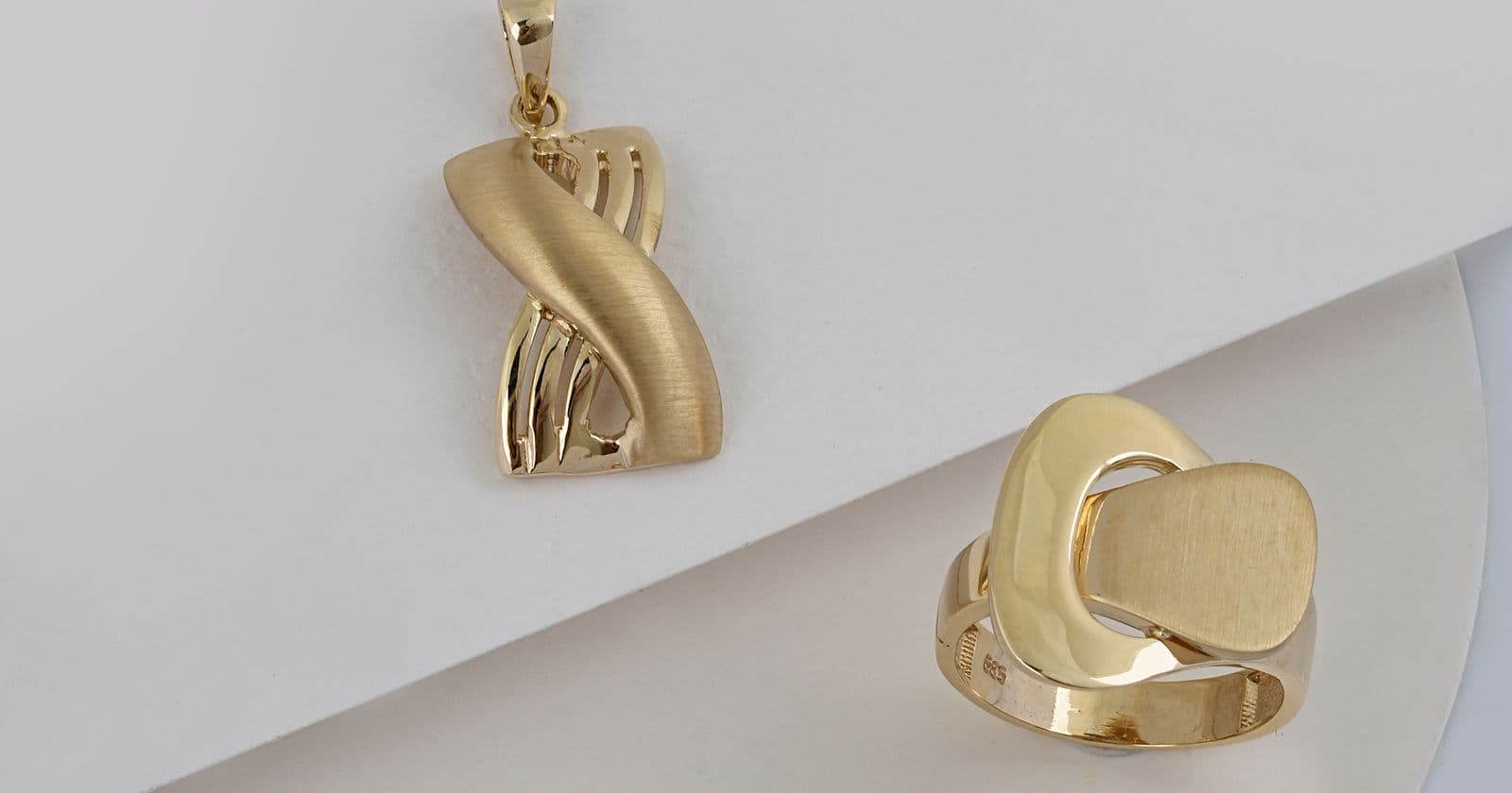 Gold pendant and ring on a white surface